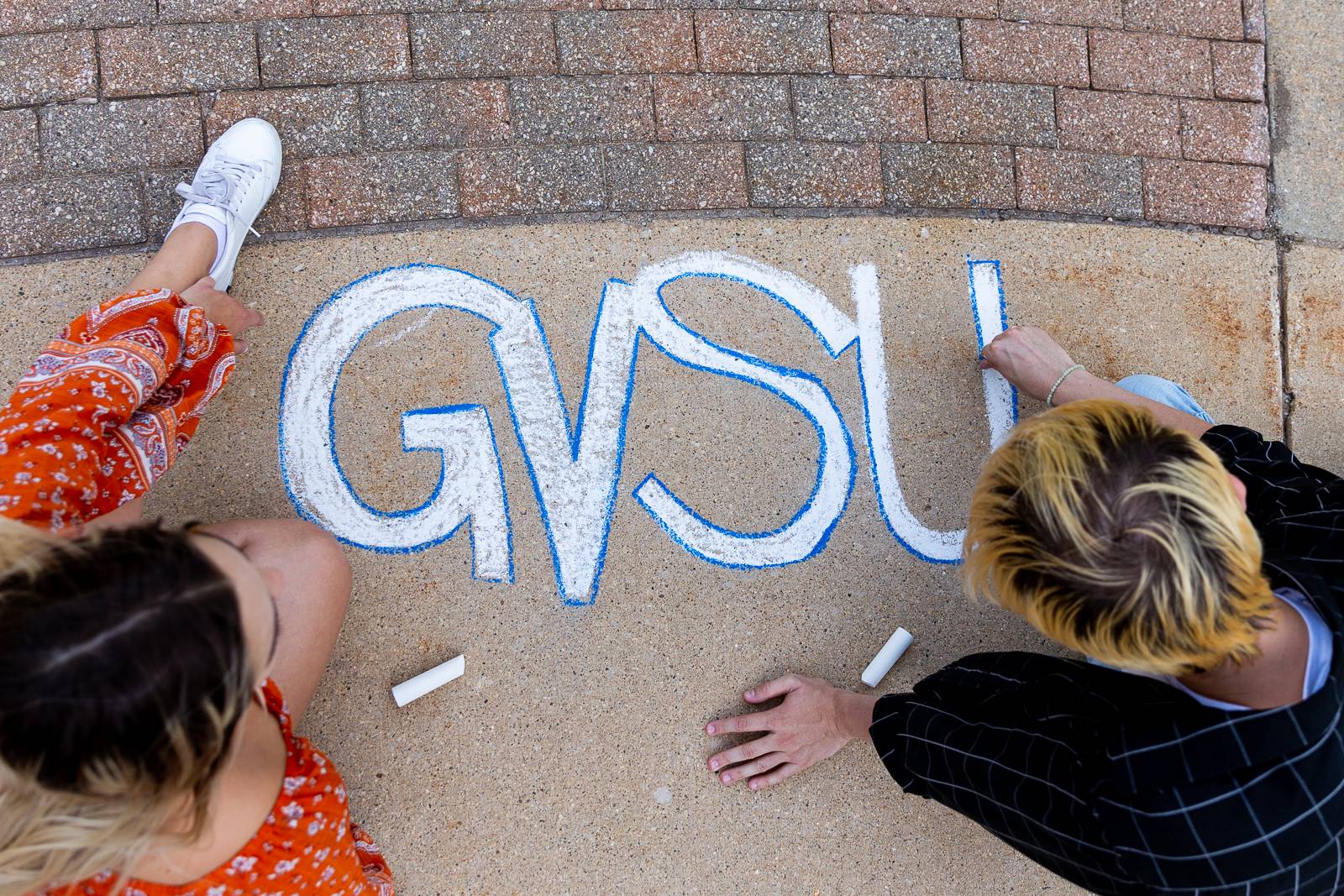 Students writing GVSU in chalk